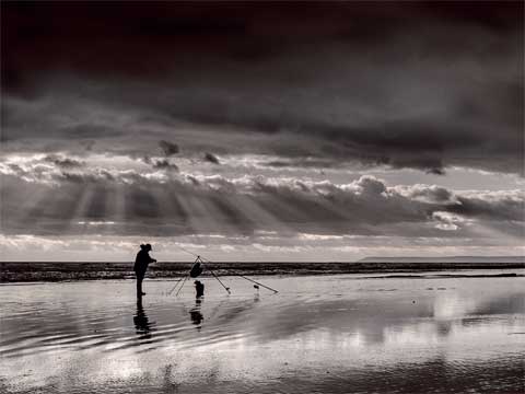 Man fishing at low tide - from the book A Wider View Bexhill-on-Sea by photographer D Charles Mason.